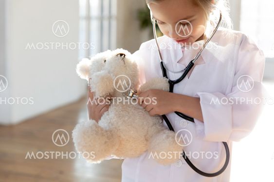 Little girl in white uniform examine plush toy