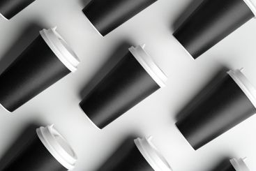 Multiple black takeaway coffee cups arranged in a...