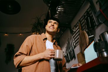 Low angle view of smiling male freelancer holding coffee...