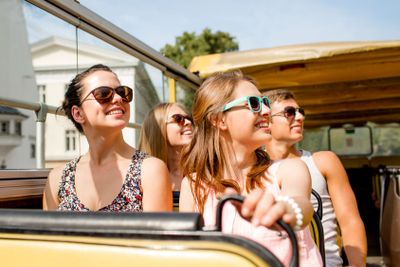 group of smiling friends traveling by tour bus