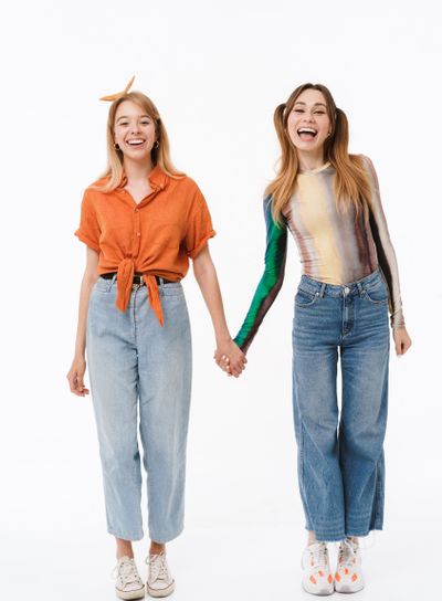 Full length photo of two pretty girls wearing colorful...