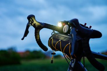Bicycle handlebar with bike light on country road at dusk