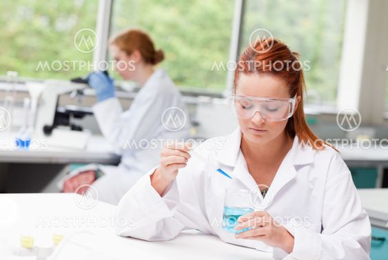 Scientist dropping blue liquid in a beaker