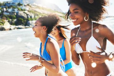 Friends, women and running in bikini by beach for fun...