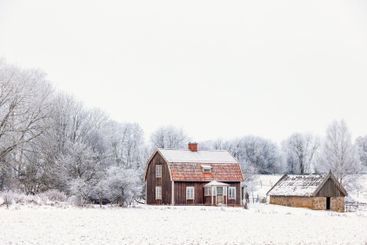 Old cottage on a snowy field in the swedish countryside