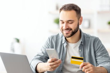 Happy Caucasian man buying things online, using...