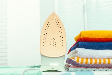 Iron on ironing board on light home interior background