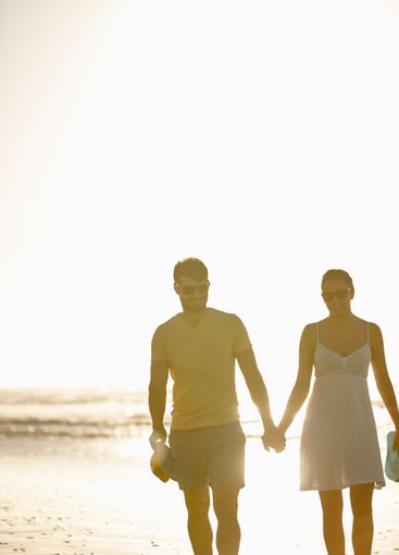 Beach, sunset and couple holding hands, walking and...
