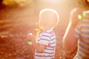 Sunshine, blowing bubbles and child in nature for fun,...