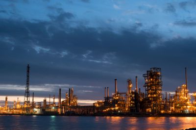 Petroleum refinery factory on water coast at dusk