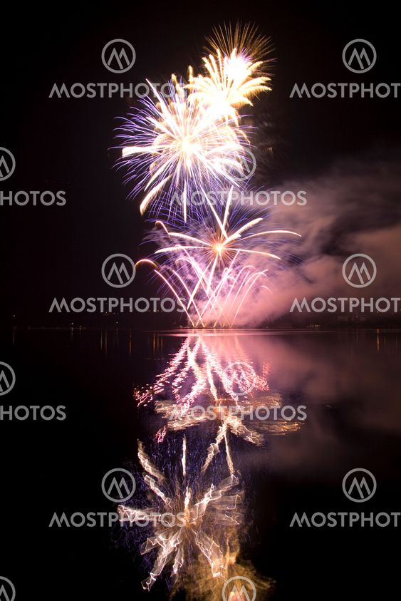 Colorful fireworks on the black sky background and water reflections