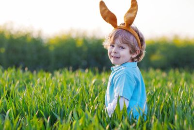 Cute little boy with Easter bunny ears  in green grass