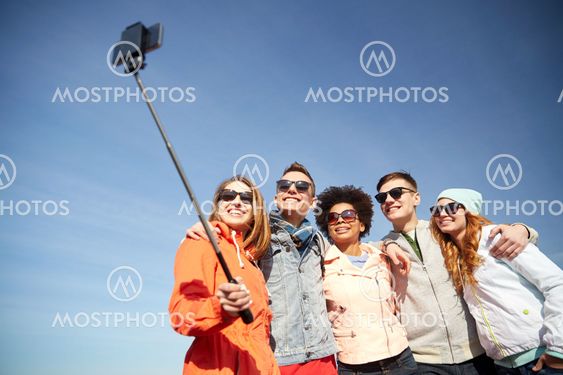 smiling friends taking selfie with smartphone