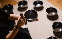 Practitioner uses singing bowls for meditation in a...