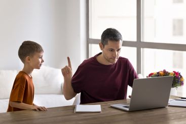 Father working on laptop while his little son asking...