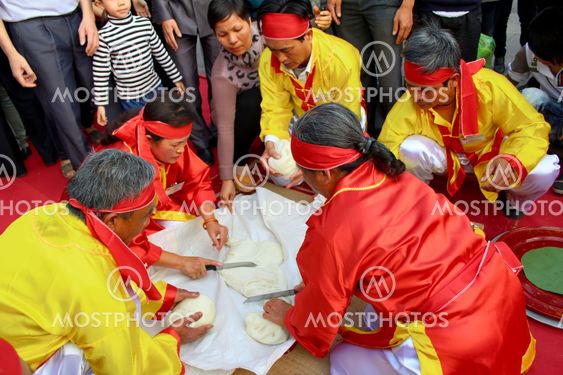 People in traditional costume exam to make round sticky...