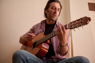 Man playing acoustic guitar indoors in a casual and...