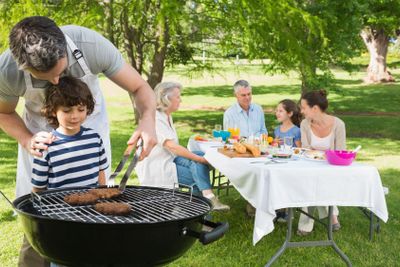 Father and son at barbecue grill with family having lunch...