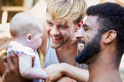 Loving Male Same Sex Couple Cuddling Baby Daughter At...