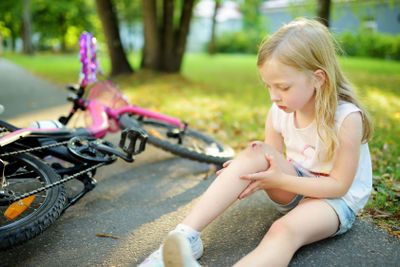Cute little girl sitting on the ground after falling off...