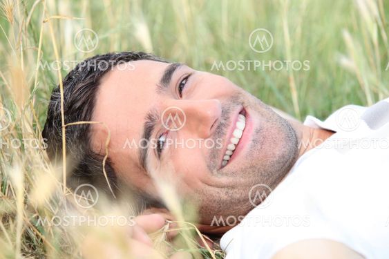 smiling 40 years old man lying down in a field