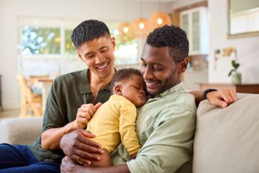 Same Sex Male Couple Or Friends Cuddling Sleeping Baby...
