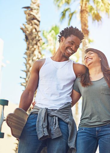 Laugh, couple and walking with skateboard in city for...