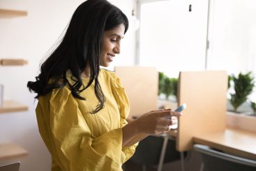 Beautiful young female student using phone at modern...