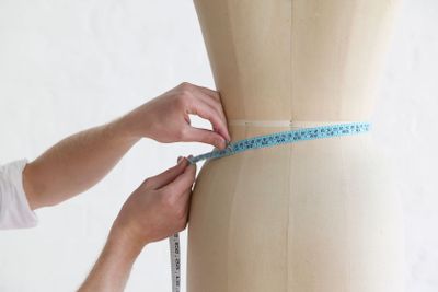 Tailor Measuring Mannequin's Waist In Studio