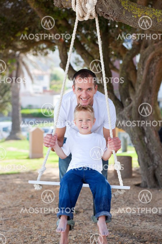 Happy father pushing his son on a swing