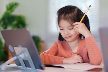 A young girl is concentrating on her homework with a...