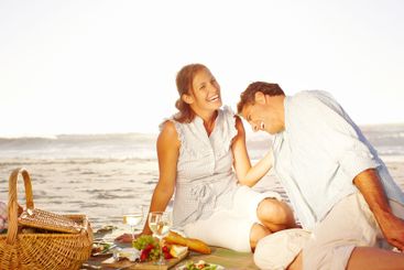 Seaside, couple and laughing on picnic with wine glass...