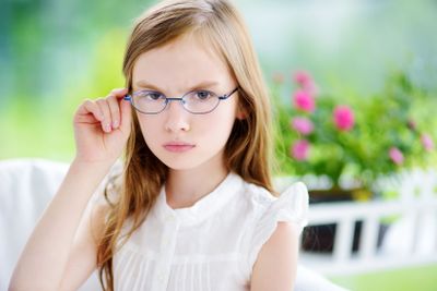 Moody little girl wearing eyeglasses feeling angry and...