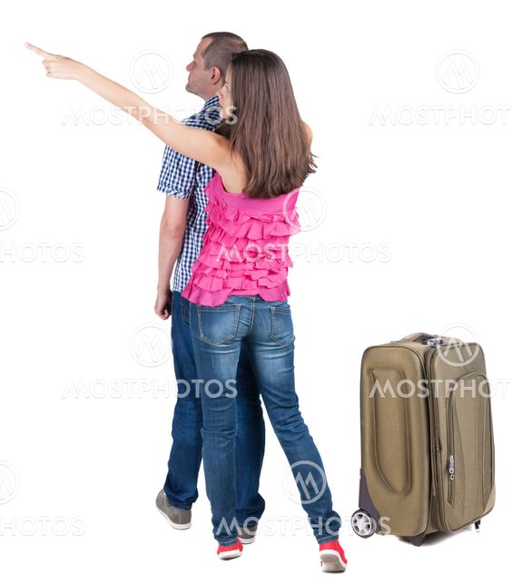 young couple traveling with suitcas and pointing at wal...