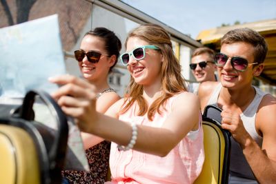 group of smiling friends traveling by tour bus