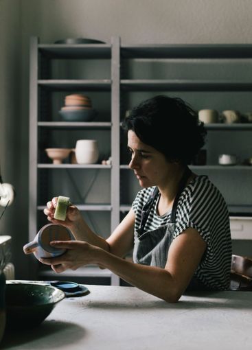 Craftswoman painting cup in ceramics store