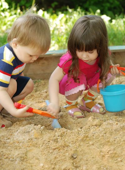 The boy and girl playing to a sandbox