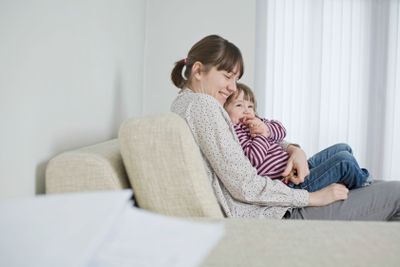 Mother And Daughter Cuddling On Sofa