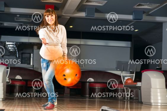 pleasant young woman throws a bowling ball
