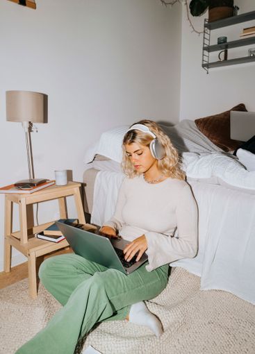 Young female student with wireless headphones using...