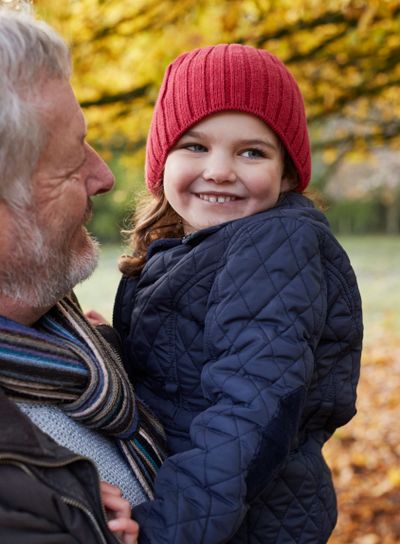 Grandfather Cuddling Granddaughter On Autumn Walk