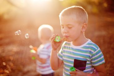 Sunlight, blowing bubbles and children in nature for...