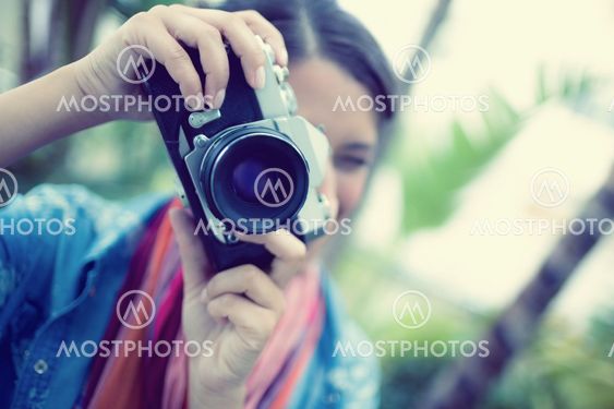 Brunette taking a photo outside looking at camera