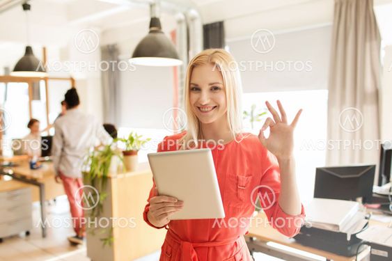 woman with tablet pc showing ok sign at office