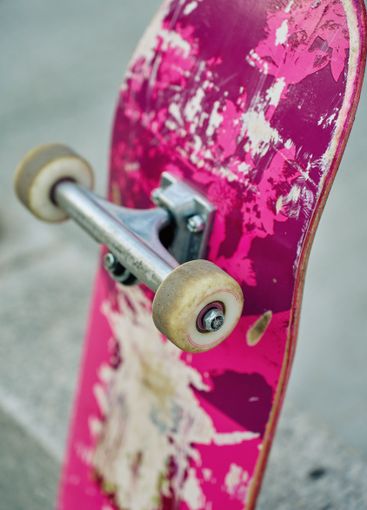 Used pink skateboard against stone wall in urban setting