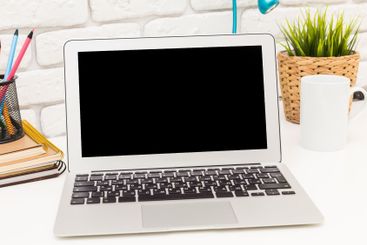 Modern workspace with a laptop, stationery, and greenery...