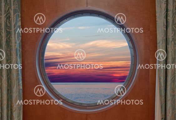 Ocean and evening sky sunset seen through the porthole of...