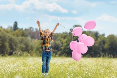 happy child with pink balloons in summer field