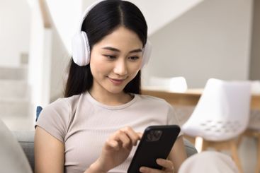 Close up of young Asian woman wear headphones using...