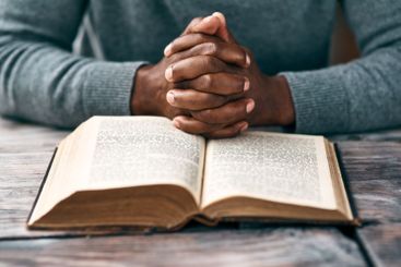 Bible, hands and Christian person reading book in...